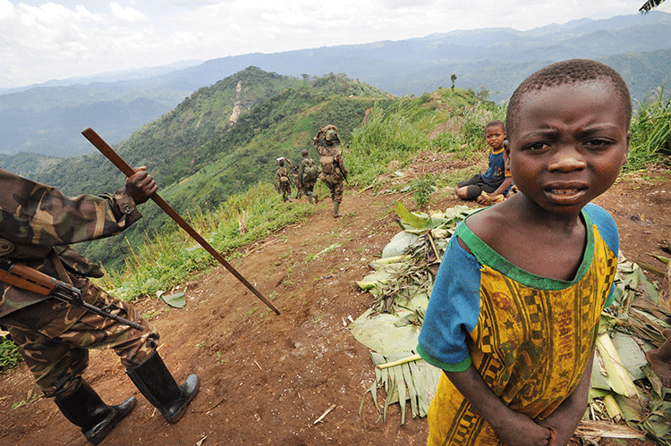 Rwandan Defense Force (RDF) troops walk thru this mountain top village in the remote reaches of Walikali district .