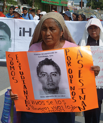 Delfina de la Cruz, mother of missing student Adán Abraján de la Cruz marches holding a sign that says: "We are the students. Why do they murder us?" Photo: Témoris Grecko