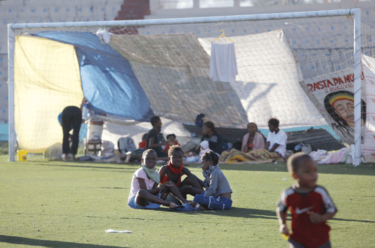 Children sit on the pitch and talk in the Sylvio Cator stadium which was used as a temporary home for many displaced people after the earthquake. Julie Jacobson/AP/Press Association Images