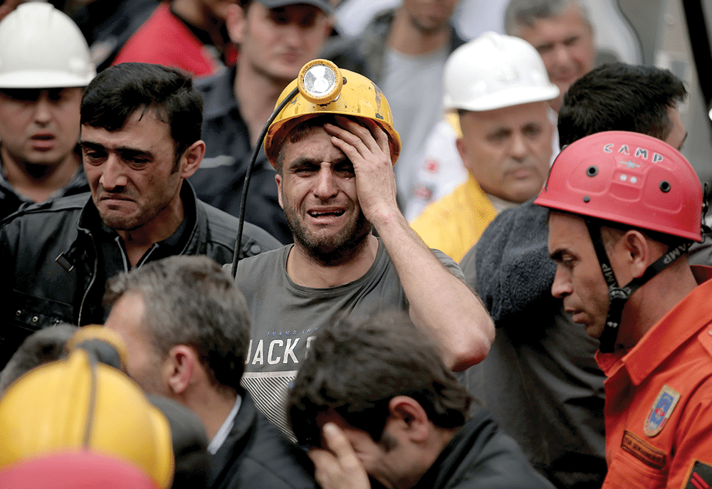 Miners watch as rescue workers carry bodies from the mine in Soma on Wednesday 14th May Photo: Emrah Gurel/AP/Press Association Images