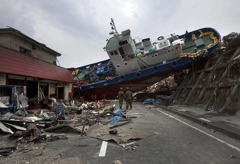 Two Japanese soldiers stop to look at a ship blocking a road they are trying to clear on 20th March 2011 after the earthquake and subsequent tsunami destroy the town of Onagawa. Photo: David Guttenfelder/AP/Press Association Images