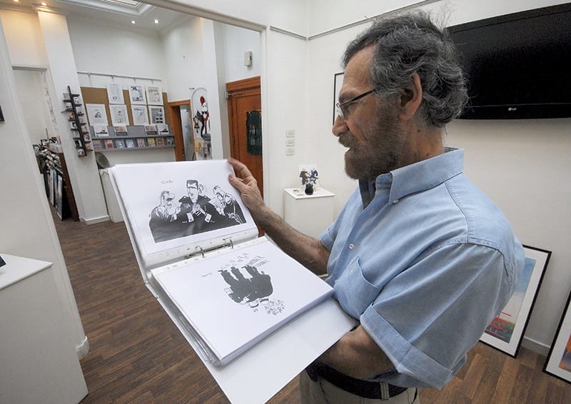 Cartoonist Ali Ferzat shows his work in August 2011, days before an attack in which his hands were broken. Photo: Muzaffar Salman/AP/Press Association Images