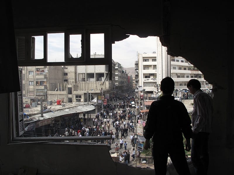 Syrian youth stand in a building damaged by tank shells in a neighborhood of Damascus, April 2012. Photo: Anonymous/AP/Press Association Images
