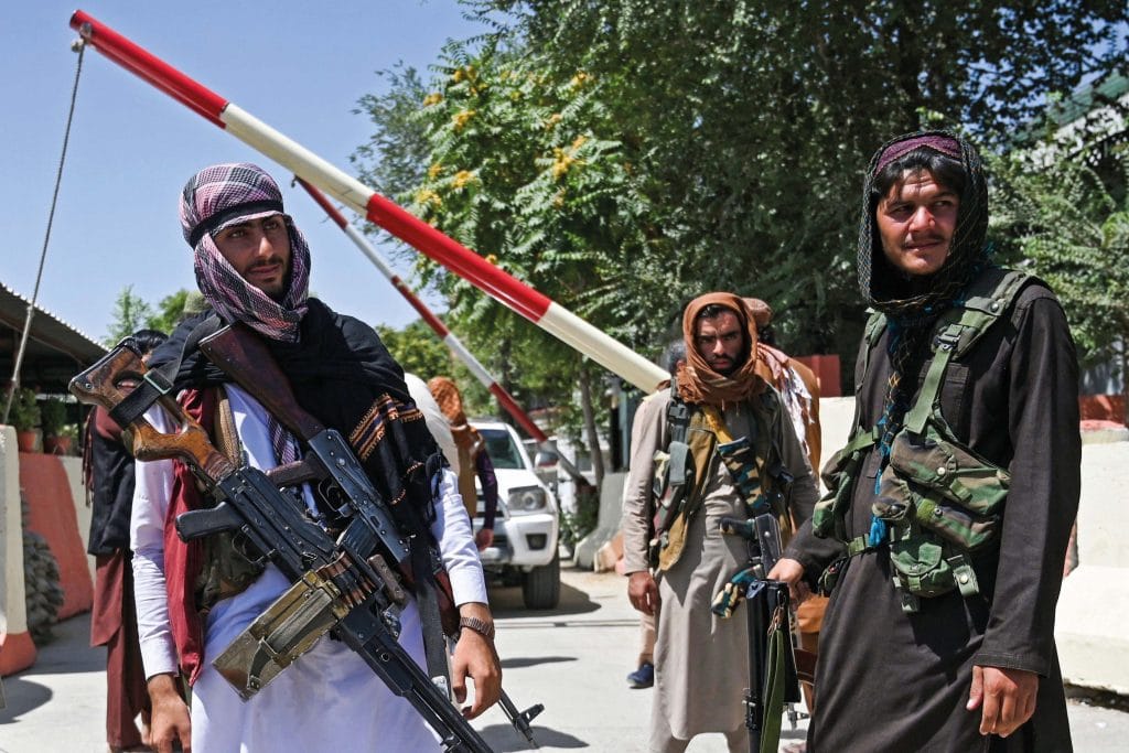 Taliban fighters stand guard along a roadside near the Zanbaq Square in Kabul