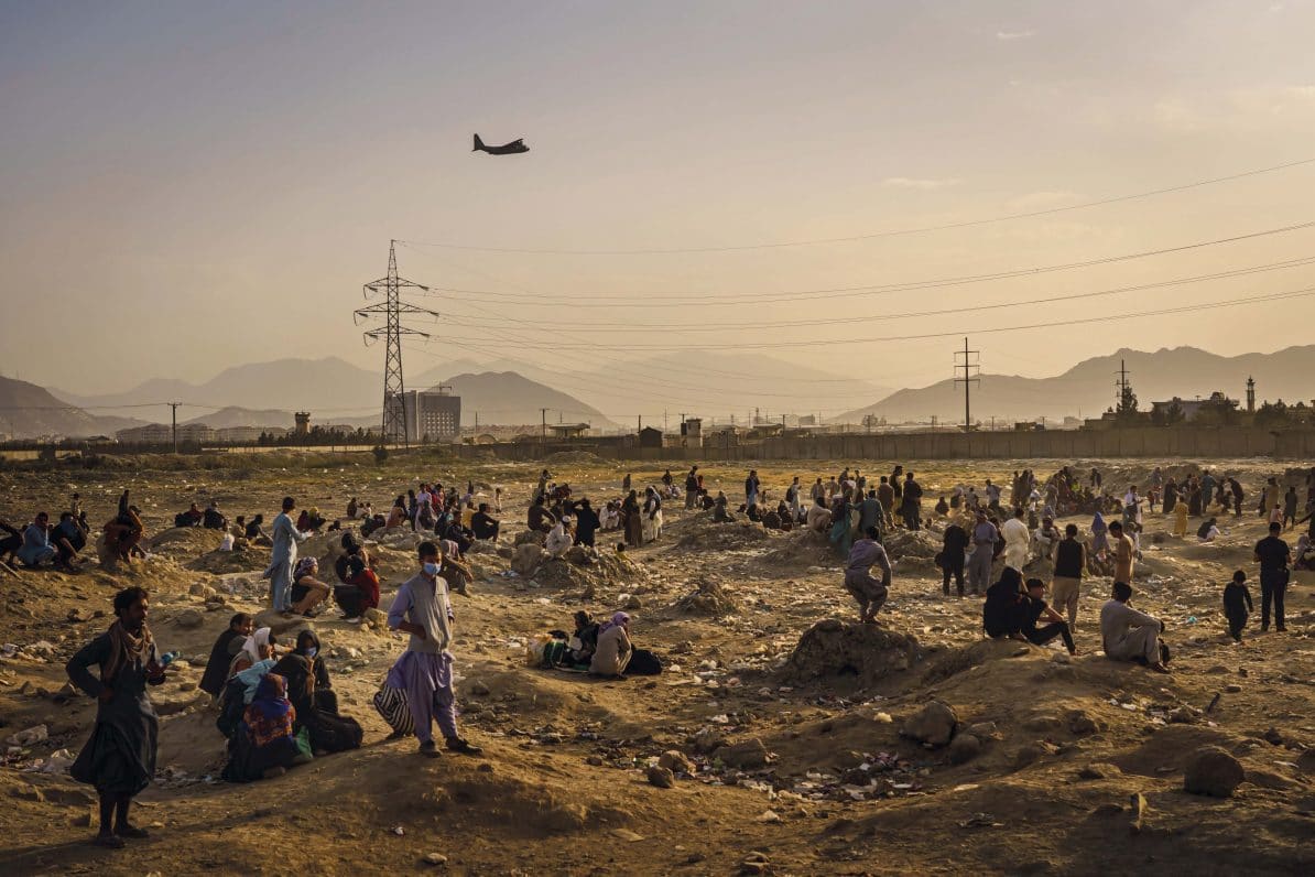 An American military transport plane takes off from Hamid Karzai International Airport in Kabul watched by Afghans who cannot get into the airport to be evacuated