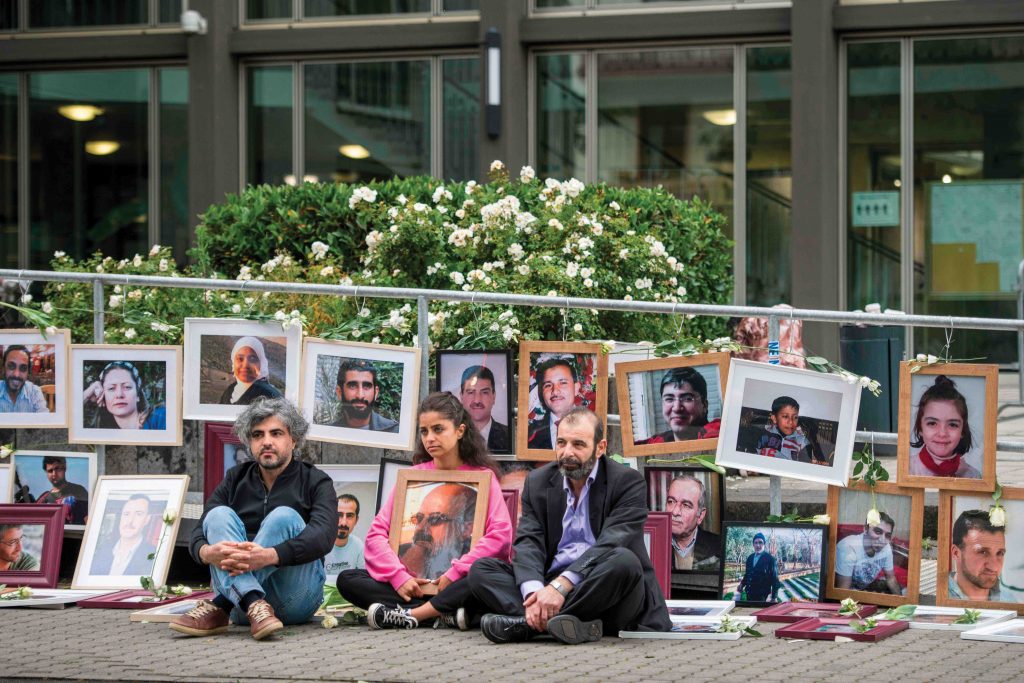 Anwar al-Bounni (right) sits alongside campaigner Wafa Mustafa (centre) and Oscar-nominated filmmaker Feras Fayyad (left) in front of pictures of victims of the Syrian regime during the trial of Anwar Raslan