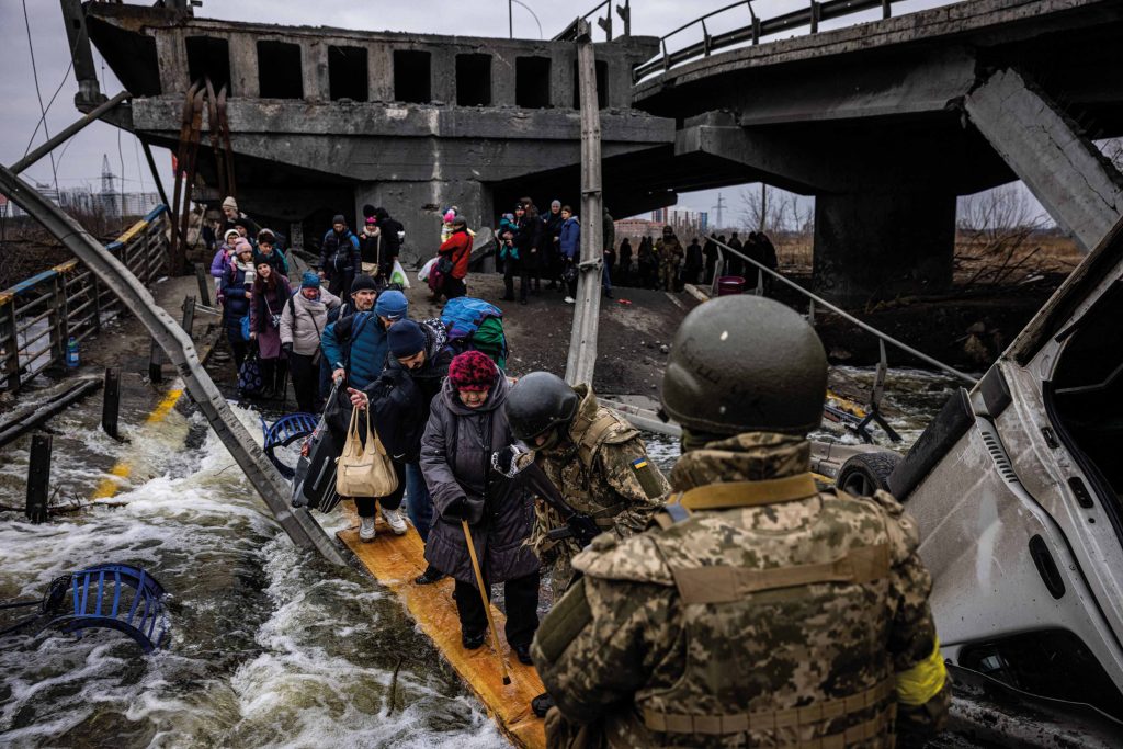 Evacuees cross a destroyed bridge as they flee the city of Irpin, northwest of Kyiv, 7th March