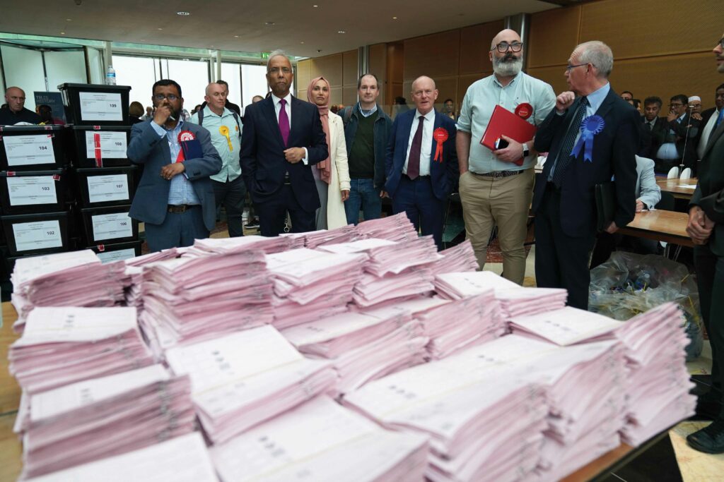 Candidates including Lutfur Rahman (third left), John Biggs (third right) and Peter Golds (right), waiting for the results at the Tower Hamlets election count in London, 6th May 2022