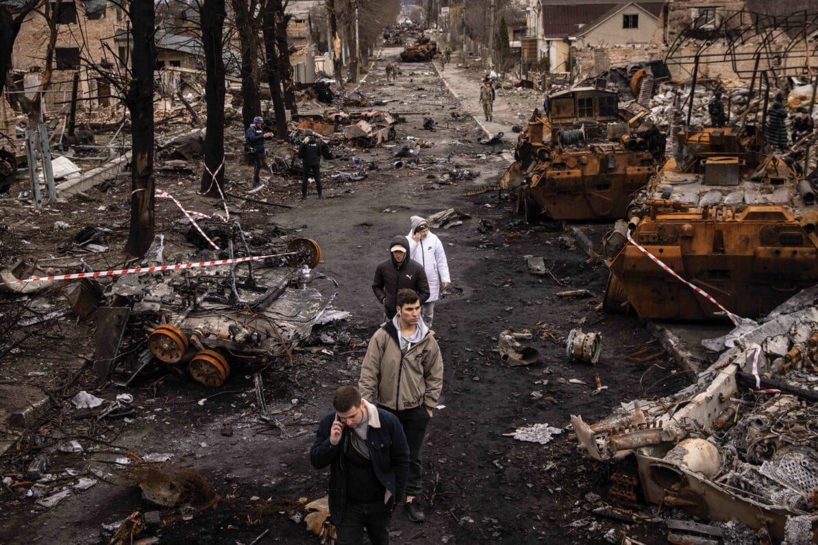 People walk through debris and destroyed Russian military vehicles on a street in Bucha, Ukraine, on 6th April 2022 in the aftermath of the Russian pull-out