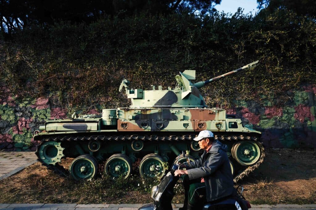 A man rides a scooter past a decommissioned tank on Lieyu, an outlying island of Kinmen that is the closest point between Taiwan and China